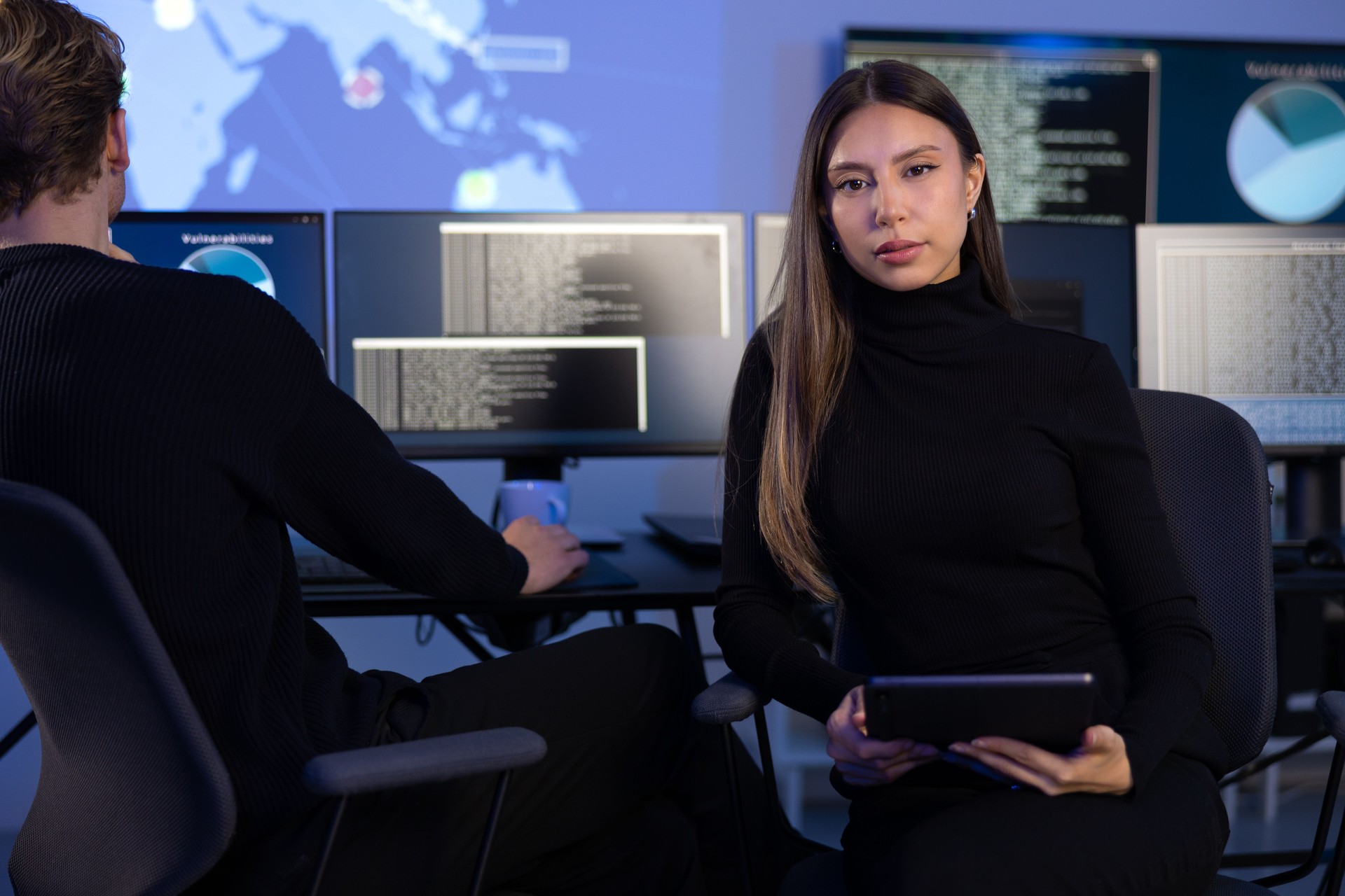 Confident female Cybersecurity Analyst or Manager in large Cyber Security Operations Center SOC handling Threats